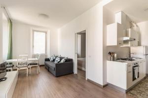 a white living room with a couch and a kitchen at Garibaldi's Apartment in Como +9 photos