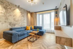 uma sala de estar com um sofá azul e uma televisão em Margi Whisky Apartament LUX AIRCON em Szczecin