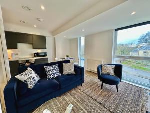 a living room with a blue couch and a chair at Serviced Apartments Nailsea in Nailsea