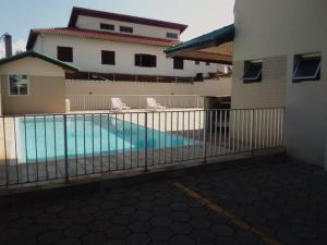 uma piscina com duas cadeiras e um edifício em AP DANTAS em Caraguatatuba