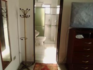 uma casa de banho com um chuveiro, um WC e um espelho. em AP DANTAS em Caraguatatuba