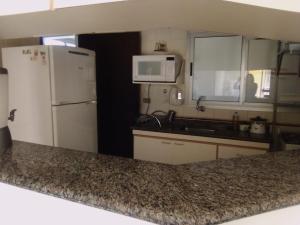 uma cozinha com um frigorífico branco e um micro-ondas em AP DANTAS em Caraguatatuba