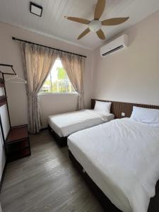 a bedroom with two beds and a ceiling fan at TANJUNG GROVE VILLAS 