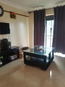 a living room with a glass table in front of a window at Good neighborhood and people around in Kampala