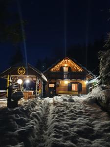 uma cabana de madeira na neve à noite em Holiday Home Prdelanca em Luče