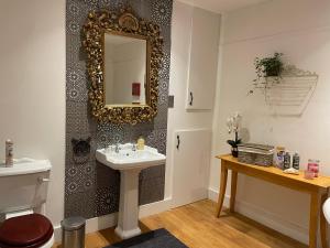 a bathroom with a sink and a mirror on a wall at Beautiful Traditional English 4 bedroom home in Greenwich in Plumstead