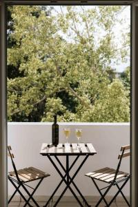 Ermis Luxury Suites & Apartments في أمودارا هيراكليو: طاولة مع كرسيين وزجاجة من النبيذ