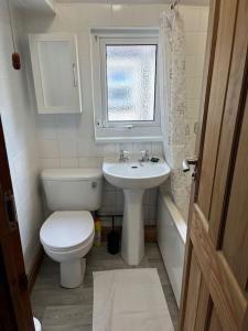 uma casa de banho com um WC, um lavatório e uma janela em Tŷ Summerfield by Dream Short Stays em Cardiff