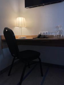 un escritorio con una silla y una lámpara. en Green Vilnius Hotel en Vilna