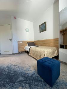 a bedroom with two beds and a blue ottoman at Green Vilnius Hotel in Vilnius