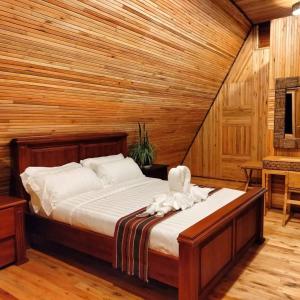 a bed in a room with a wooden wall at Nsaho resort in Fort Portal