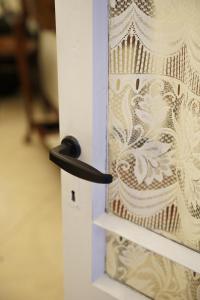 a door with a white curtain with a black handle at Lantern Stay in Marsalforn