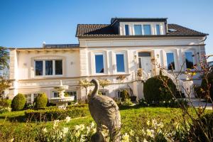 ein großes weißes Haus mit einer Statue davor in der Unterkunft Villa Rosengarten auf der Sonneninsel Fehmarn in Fehmarn