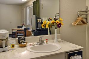 baño con lavabo, espejo y flores en Super 8 by Wyndham Red Bluff, en Red Bluff