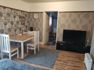 a living room with a table and a television at Bright Park Inn in Peterborough