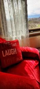 un sofá rojo con una almohada roja frente a una ventana en Σοφίτα " Μαργαρίτα ", en Tríkala