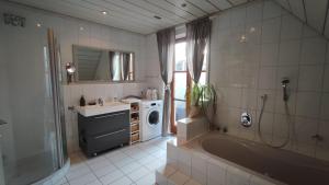a bathroom with a tub and a sink and a washing machine at HOMELY STAY in a MODERN GREEN DREAM in Dachau