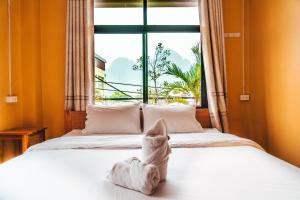 a cat is sitting on a bed in front of a window at Vang Vieng Sunset Guesthouse & Restaurant in Vang Vieng