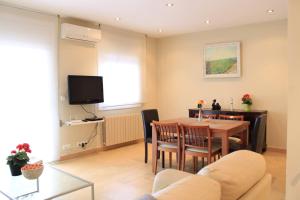 - un salon avec une table, des chaises et une télévision dans l'établissement Can Robert Apartment by SitgesNow, à Sitges
