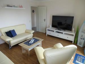 a living room with white furniture and a flat screen tv at Scheitz 3 in Dahme
