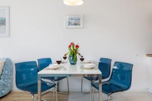 a table with blue chairs and a vase of flowers at Wellness & SPA Resort Aquamarine Apartment by Renters in Dziwnów