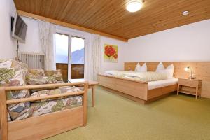 a bedroom with two beds and a couch and a television at Gästehaus Rundblick in Schruns