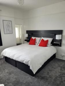 um quarto com uma grande cama branca com almofadas vermelhas em Edelweiss Guest House em Southend-on-Sea