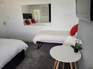 Habitación con 2 camas, mesa y espejo. en Edelweiss Guest House en Southend-on-Sea
