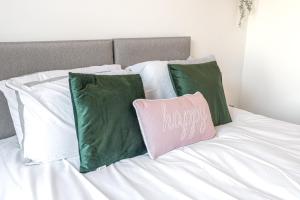 a bed with green and white pillows and a happy pillow at Spacious 3 Bedroom Apartment in Barrow in Furness