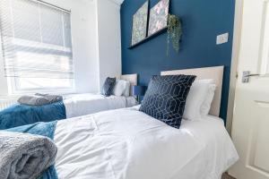 sypialnia z 2 łóżkami i niebieską ścianą w obiekcie Spacious 3 Bedroom Apartment w mieście Barrow in Furness