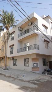 a white building with a palm tree in front of it at Al Rasheed Apartments second floor apartment in Karachi