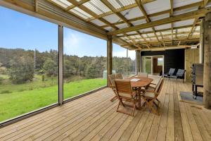 una terrazza in legno con tavolo e sedie. di Waimate Farmstay - Kerikeri Holiday Home a Kerikeri