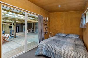 1 dormitorio con 1 cama y puerta corredera de cristal en Waimate Farmstay - Kerikeri Holiday Home, en Kerikeri