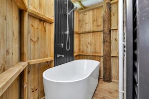 baño con bañera blanca y paredes de madera en Waimate Farmstay - Kerikeri Holiday Home en Kerikeri