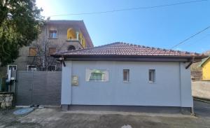 ein kleines weißes Haus mit einem Zaun davor in der Unterkunft Marcos Apartments Victoriei - self check-in in Reşiţa