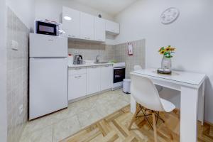 a white kitchen with a white refrigerator and a table at Apartment Makao in Podgorica