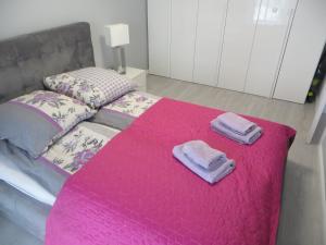 - un lit avec 2 serviettes sur une couverture rose dans l'établissement GARDENIA Apartament Przy Plaży 17, à Dziwnów