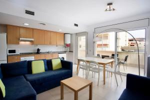 ein Wohnzimmer mit einem blauen Sofa und einem Tisch in der Unterkunft ENJOY your HOLIDAYS with us !!, TERRACE 25m2 - Apartment 65m2 3 Bedrooms, Capacity 4-6pers, WIFI, IDEAL to DIGITAL NOMAD Beach 5min walking, 4 Pools, Parking Opt, Air Conditioning in Lloret de Mar