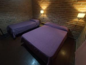 twee bedden in een kamer met een bakstenen muur bij Sierras Alojamiento in Mina Clavero