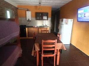 a kitchen with a table with chairs and a refrigerator at Sierras Alojamiento in Mina Clavero