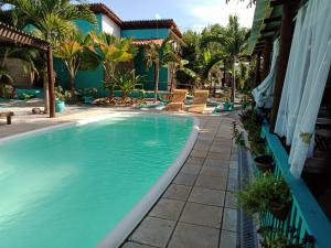 a swimming pool in front of a house with palm trees at Gostoso Sol e Mar Pousada in São Miguel do Gostoso