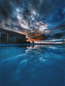 ein großer Pool mit wolkigem Himmel darüber in der Unterkunft Mosteiros Place in Mosteiros