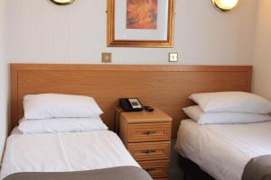 ein Hotelzimmer mit 2 Betten und einem Telefon auf einem Nachttisch in der Unterkunft Regency Hotel Westend in London