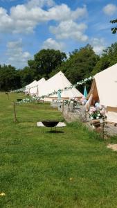 a row of white tents in a field at Hopgarden Glamping - Luxury 6m bell tent in Wadhurst