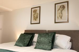 a bed with two green pillows and two pictures on the wall at Fast Wi-FI, Smart TV, Sleeps up to 3, on street parking in Lincolnshire