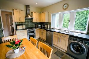 a kitchen with a table and a sink and a dishwasher at Calder Cottage in The Ribble Valley in Whalley