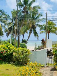 a gate to a beach with palm trees and flowers at Villa Luana Yuna in Au Cap