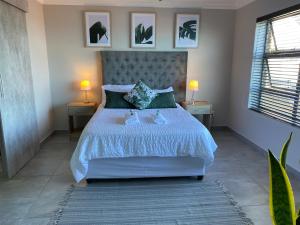 1 dormitorio con 1 cama grande, 2 mesas y 2 lámparas en Tulip On The Bay en Mossel Bay