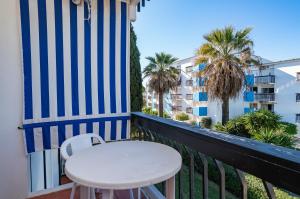 einen weißen Tisch und einen Stuhl auf einem Balkon mit Palmen in der Unterkunft Lago Azul 2 in Quarteira