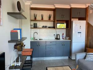 a kitchen with blue cabinets and a white refrigerator at Tulip On The Bay in Mossel Bay